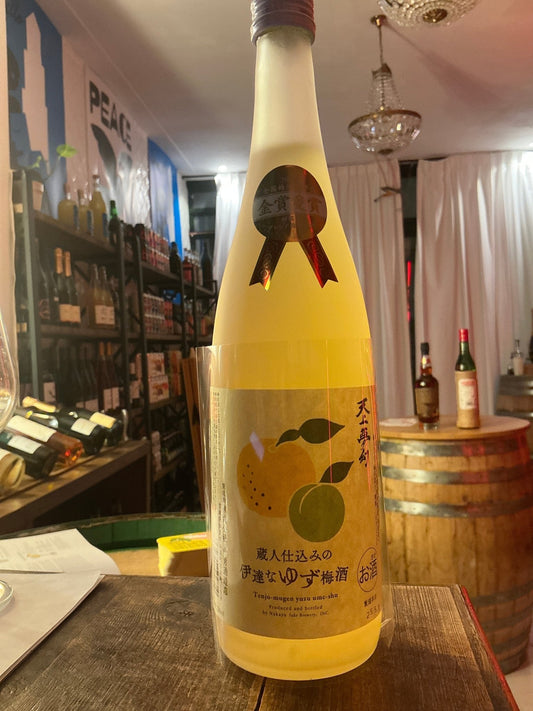 Tall frosted glass bottle of Tenjo Mugen Date na Yuzu Ume-shu liqueur with yellow citrus fruit illustrations, premium.