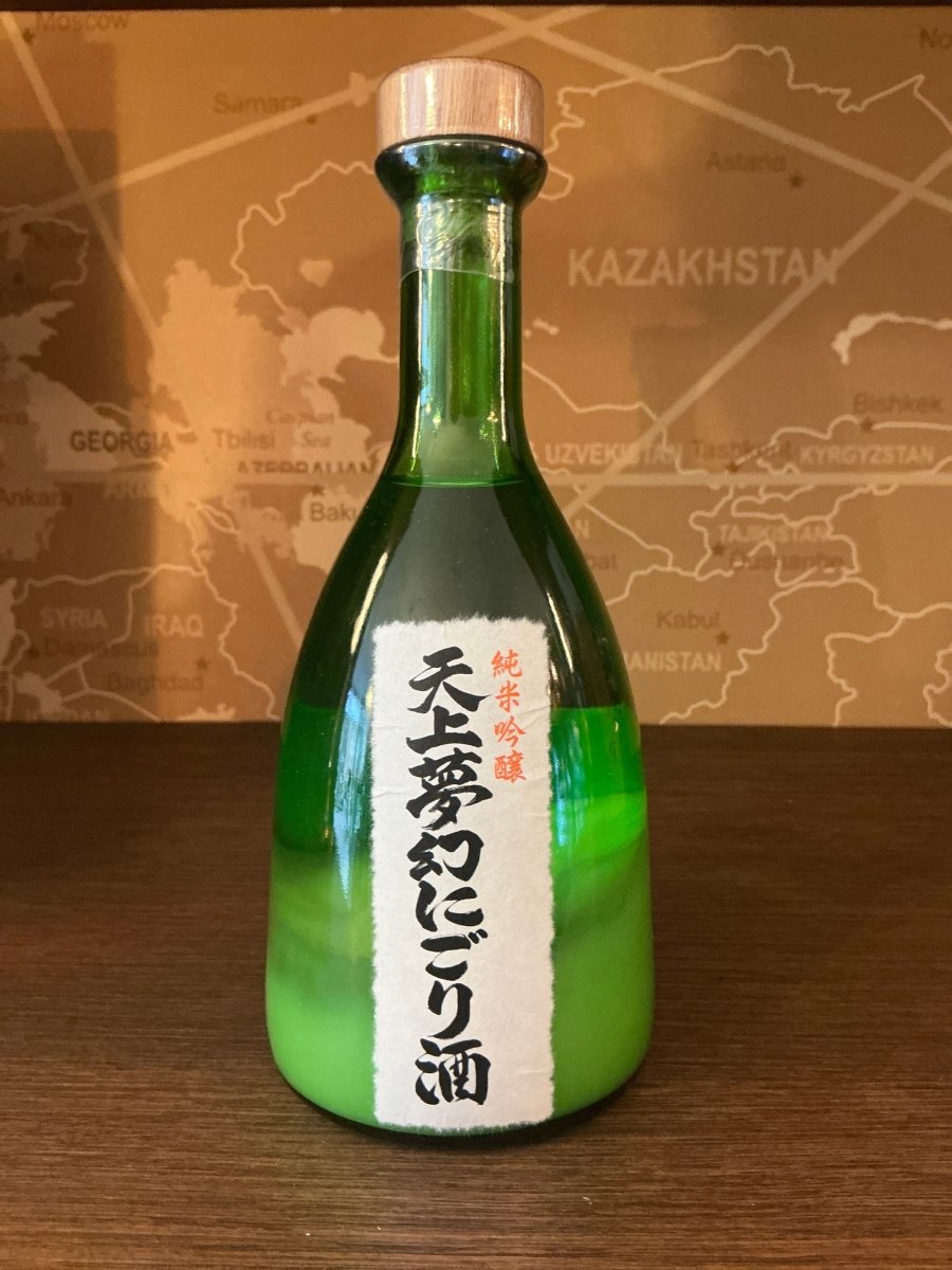 Tenjo Mugen Junmai Ginjo Nigori sake in a wide-based green glass bottle with white washi label and Japanese calligraphy by Nakayu Shuzoten