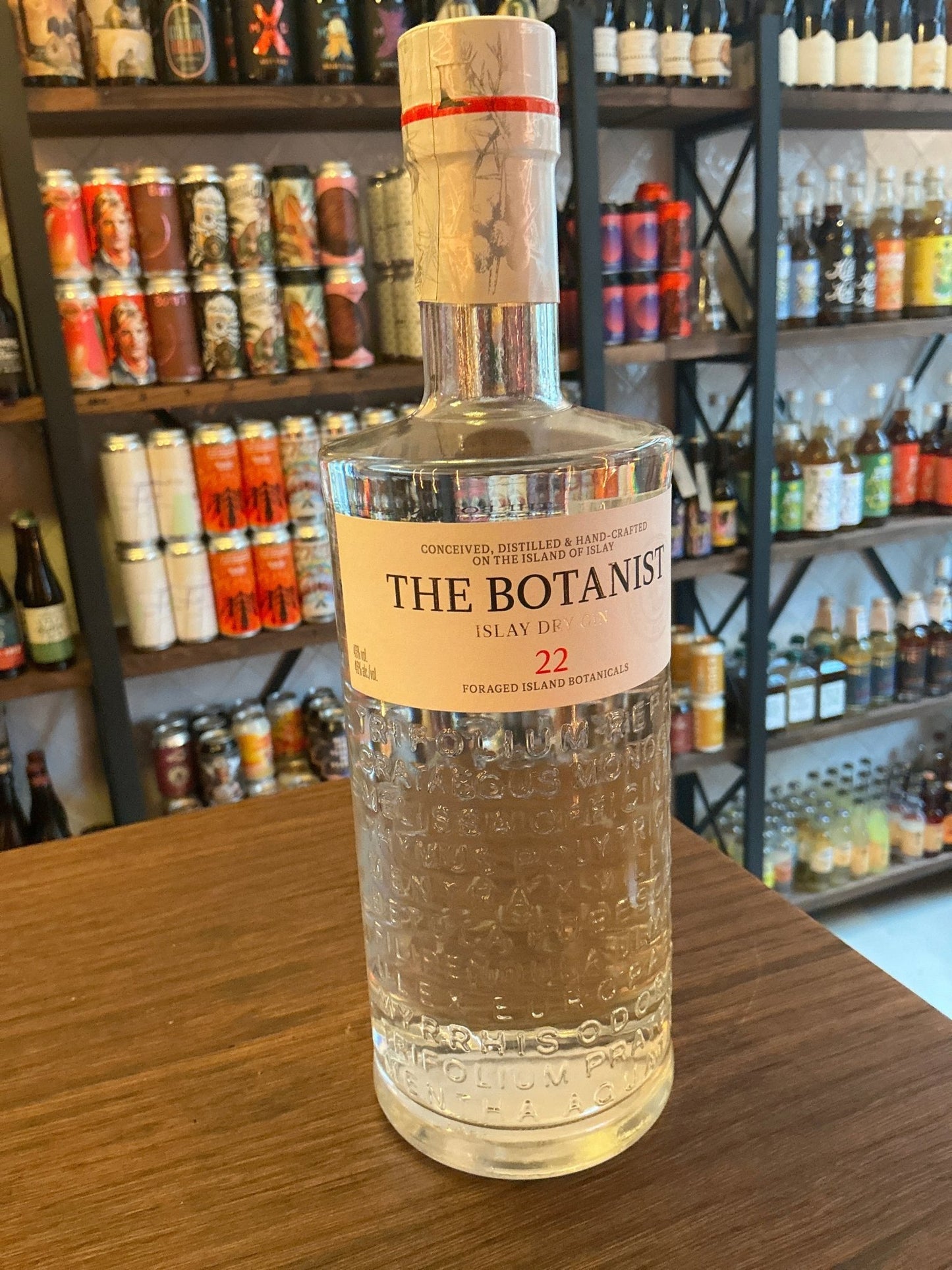 Clear glass bottle of The Botanist Islay Dry Gin with textured botanical design, sealed with natural cork and red wax,.