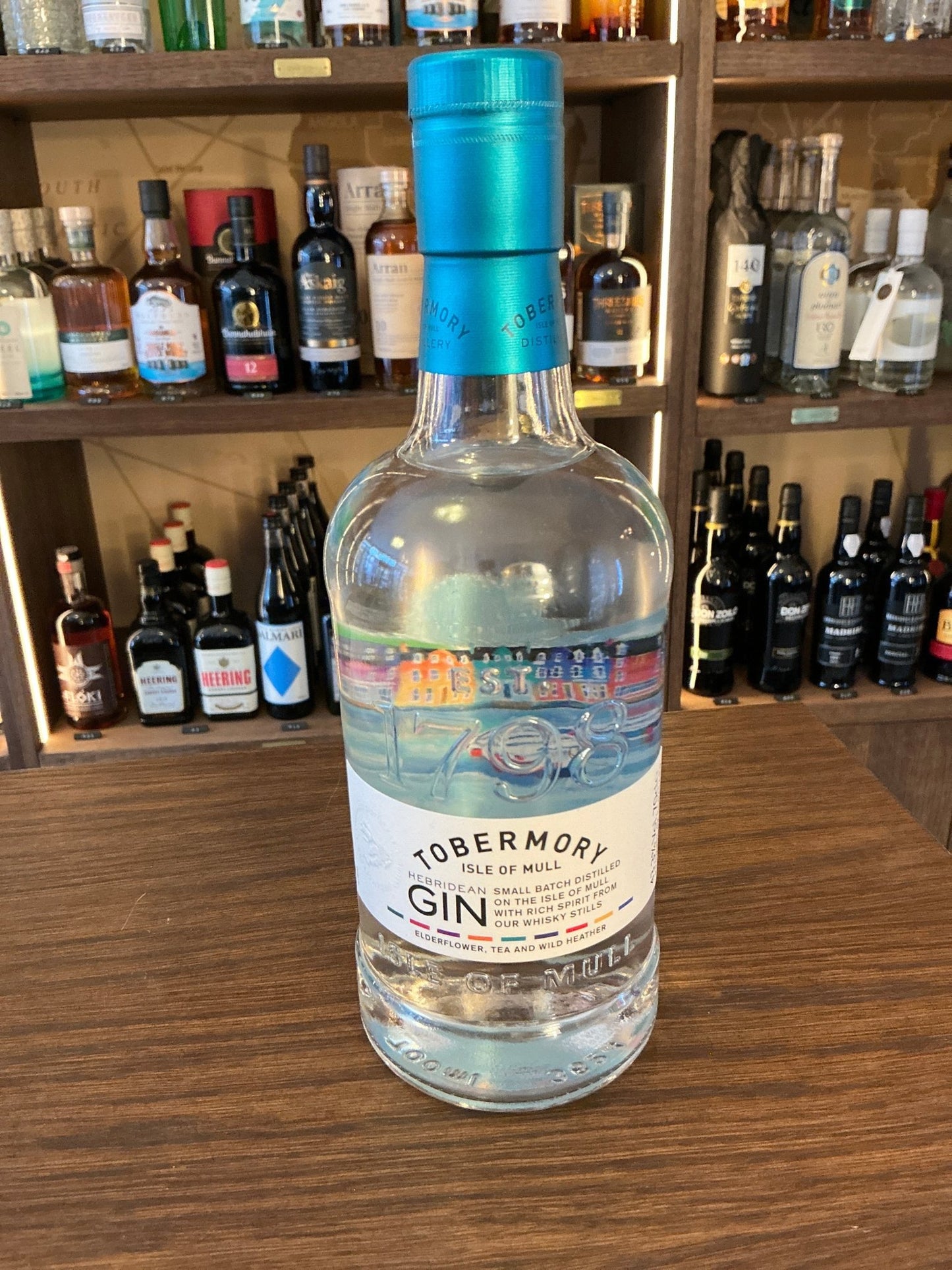 Tobermory Gin small batch artisan bottle with blue cap, premium distilled botanical spirit on wooden bar counter.