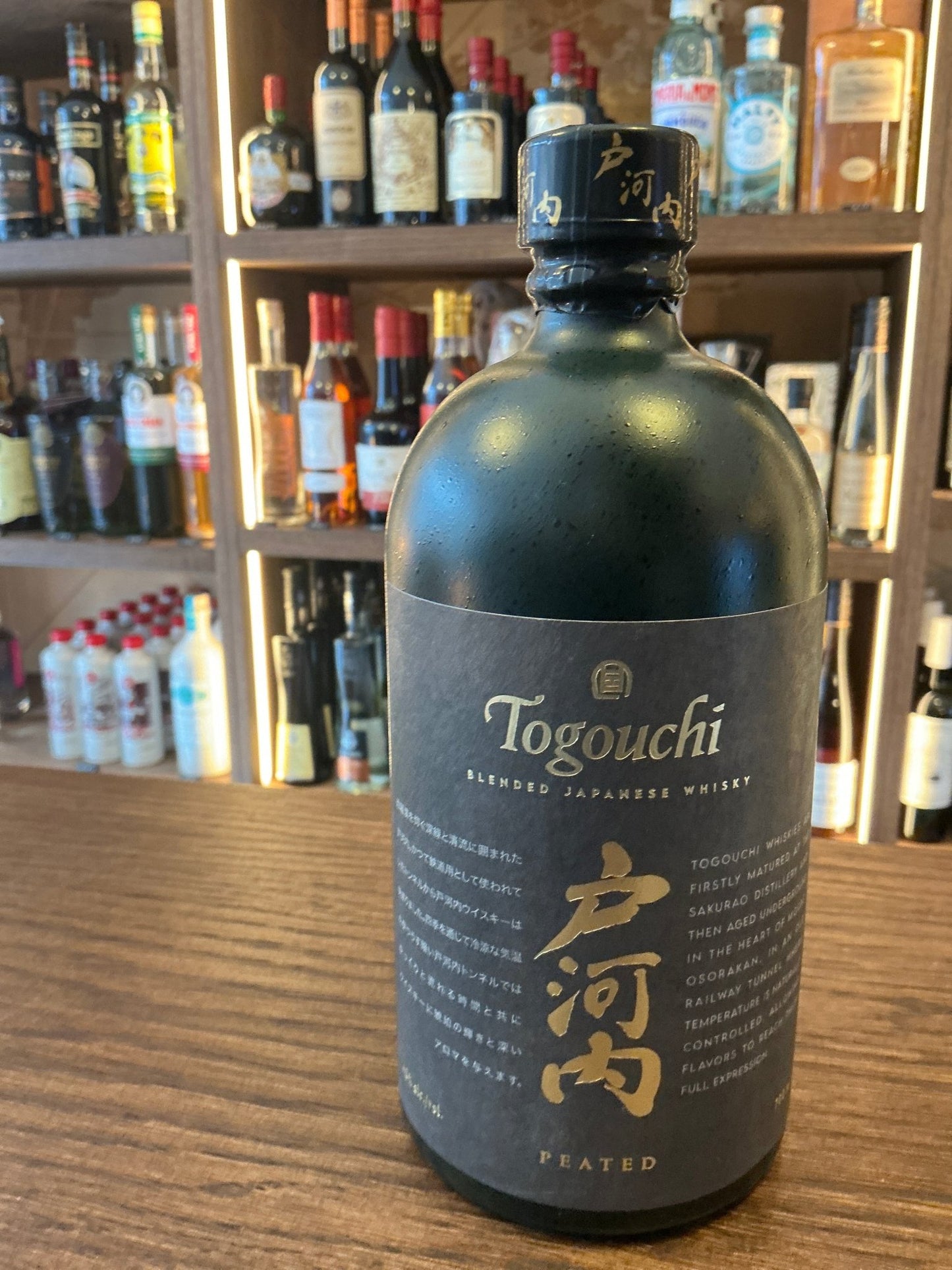 Matte black bottle of Togouchi Peated Single Malt Japanese whisky with gold accents, premium small batch artisan spirit on.