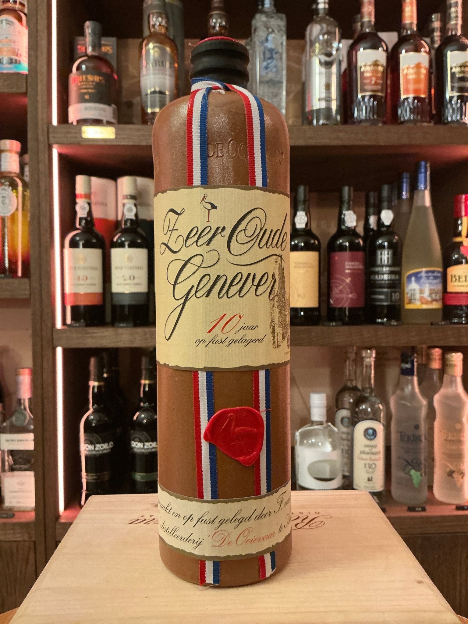 Van Wees Zeer Oude Genever 10 Year aged Dutch gin with botanical, spiced flavor in tall glass bottle with tricolor ribbon.