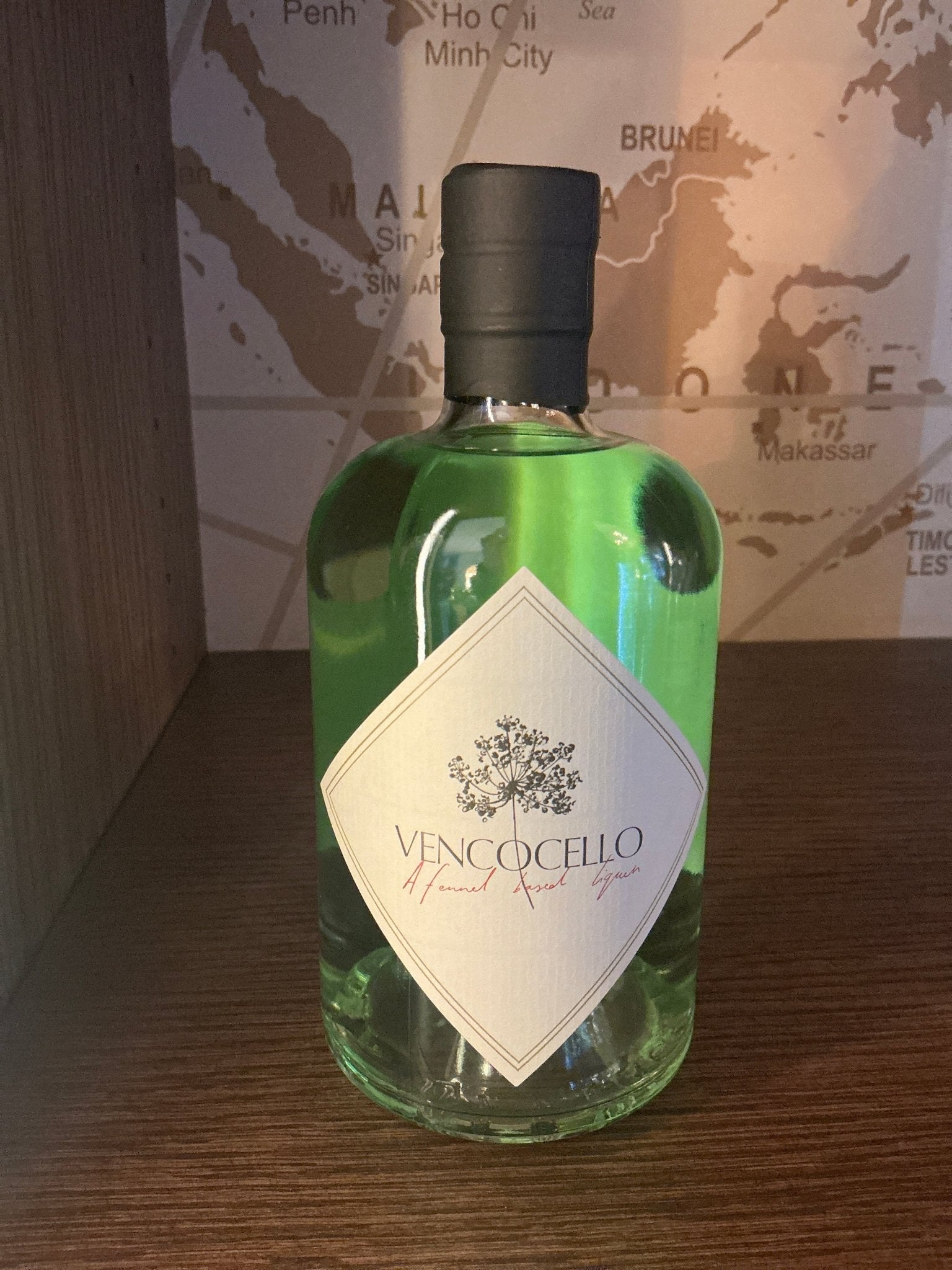 Green glass bottle of Vencocello Dutch Fennel Liqueur with black cap and white diamond-shaped label highlighting premium.