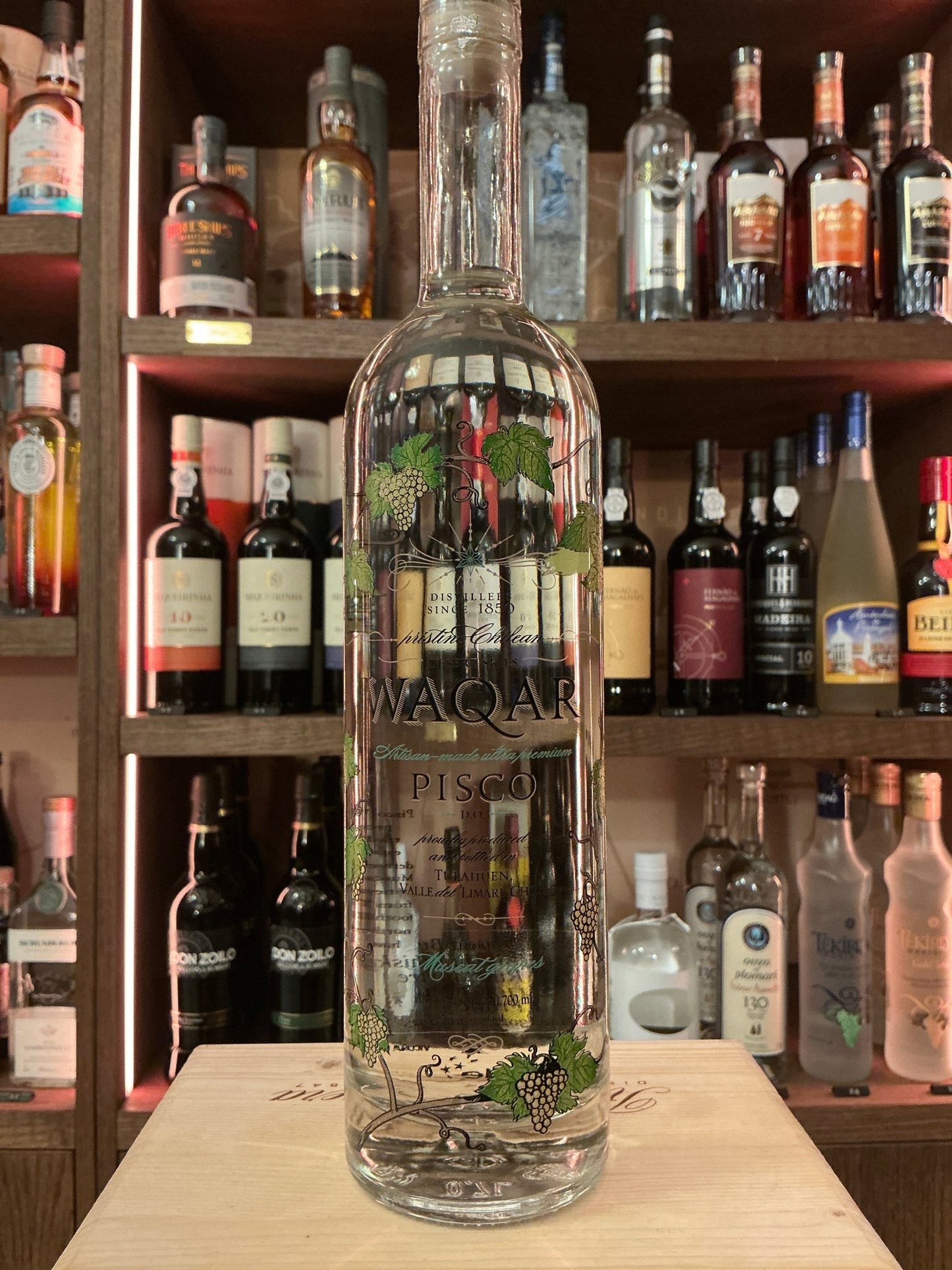 Waqar Pisco clear glass bottle with botanical design on label, premium small batch distilled Chilean spirit, artisan.