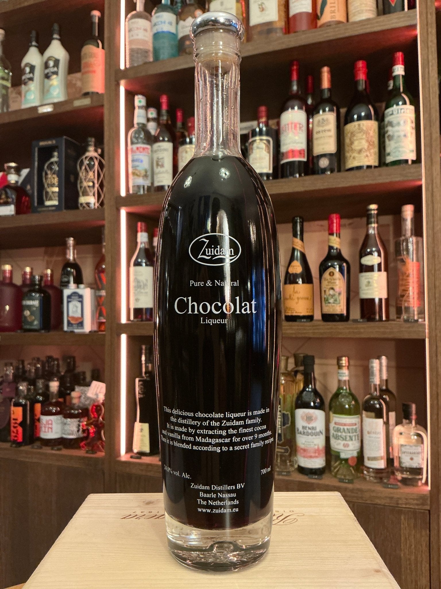 Tall slender bottle of Zuidam Chocolate Liqueur with clear glass showcasing dark rich liqueur, labeled artisan Dutch.